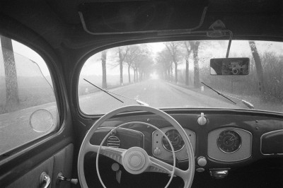 Fotograaf Daan Scholte via de achteruitkijkspiegel van zijn Volkswagen, op de rijksweg ten zuiden van Oss, ca. 1960 (foto: Daan Scholte, collectie Stadsarchief Oss nr. DSN1344_44395)