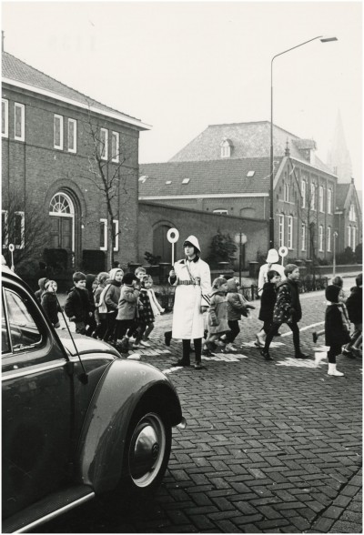 Een klaar-over helpt kindern oversteken in Veldhoven, 1950