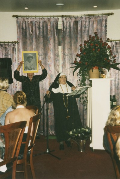 Ria van Dijk geeft verkleed in habijt een voordracht tijdens een zeventigste verjaardag in 1997.