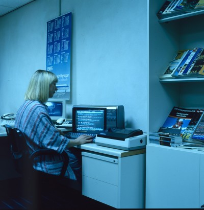 Medewerker van een reisbureau werkt achter een computer, Tilburg 1984 (foto: Frans van Aarle, collectie Regionaal Archief Tilburg nr. 1237_9_645_002) 